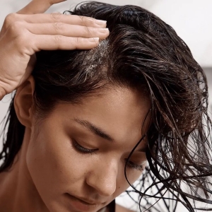 Frau trägt Kopfhautpeeling auf